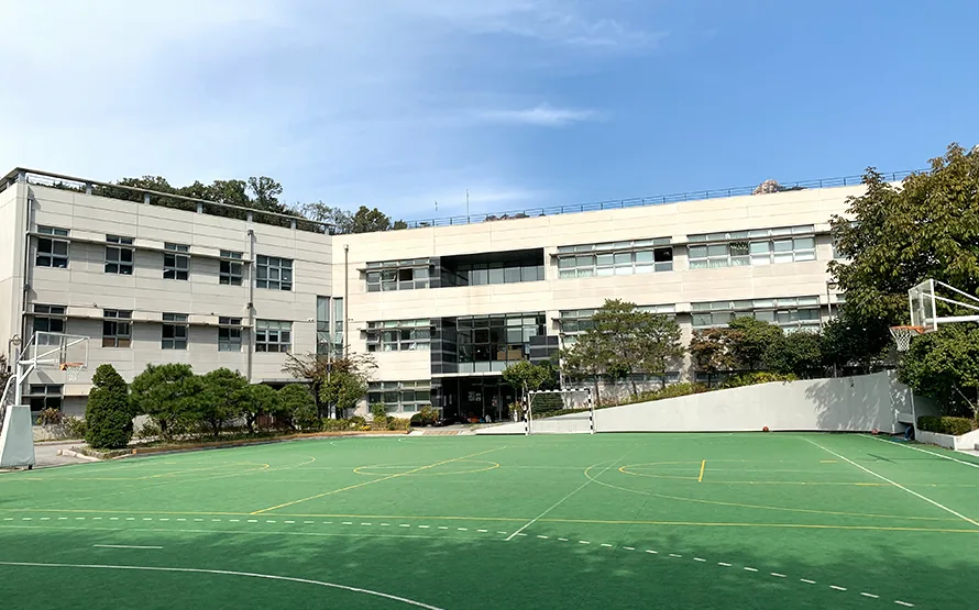 Le campus du Lycée International Xavier à Séoul : le terrain de sport et les bâtiments de l'école sous un ciel bleu