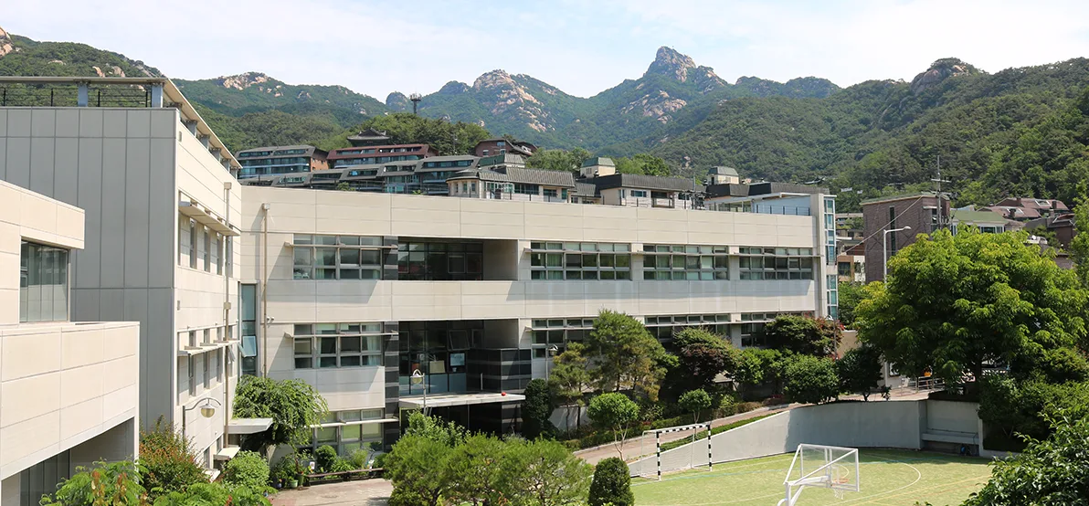 Les bâtiments du lycée et son terrain de sport, devant les sommets du Bukhansan.